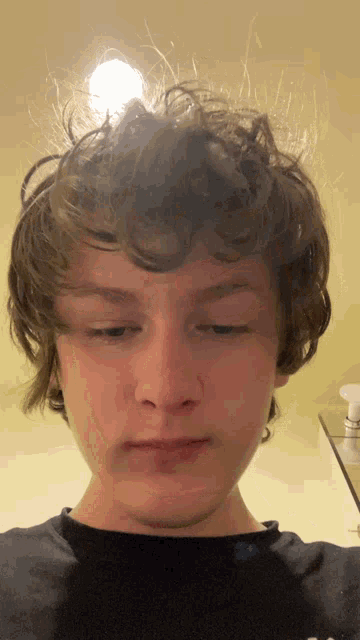 a young man with curly hair is wearing a black shirt