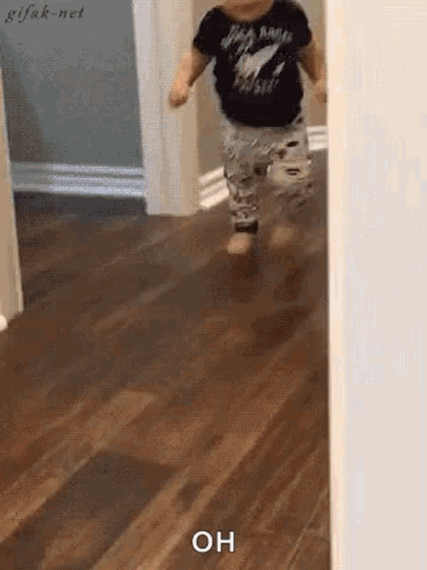 a baby is walking on a wooden floor and the word oh is on the floor .