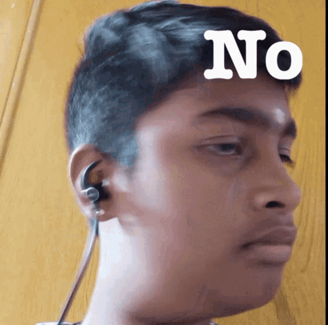 a young boy wearing ear buds has the word no on his head