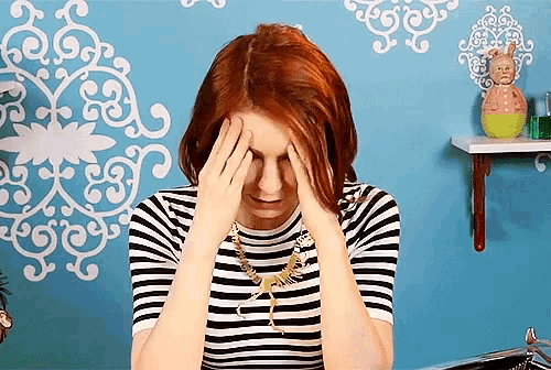 a woman covering her face with her hands in front of a blue wall