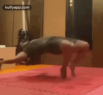 a man is doing push ups on a mat in a gym .