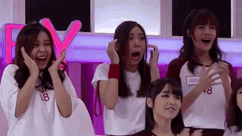 a group of young women are standing next to each other on a stage and laughing .