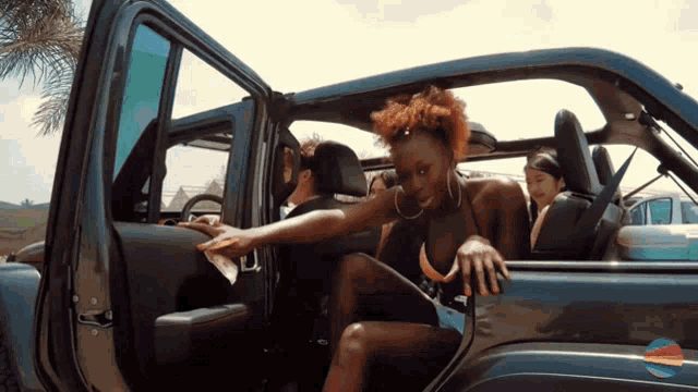 a woman in a bikini is leaning out of a car door
