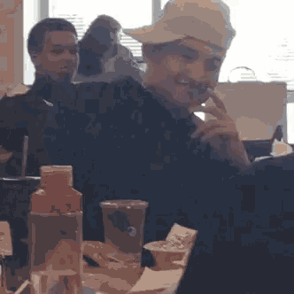 a man wearing a hat is sitting at a table .