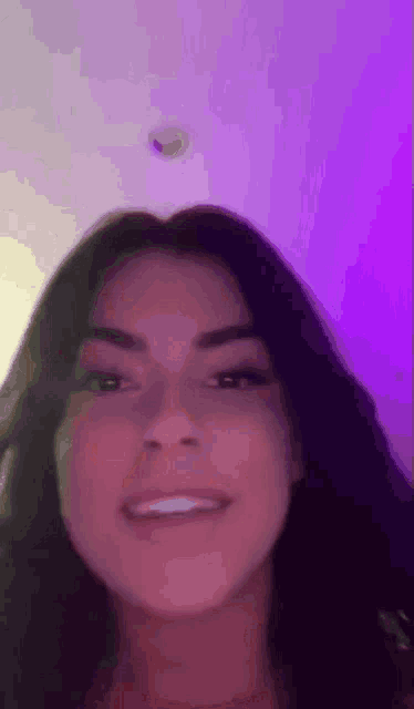 a close up of a woman 's face in front of a purple background .