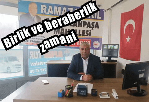 a man sits at a desk in front of a sign that says ramazan