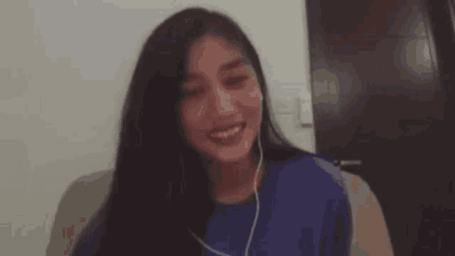 a woman wearing headphones is sitting on a couch and looking at the camera .