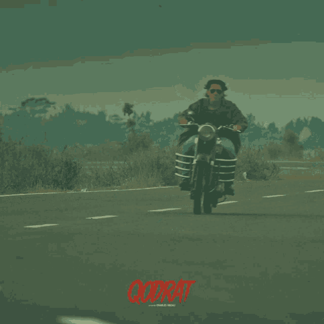 a man is riding a motorcycle on a road with the word godrat in red