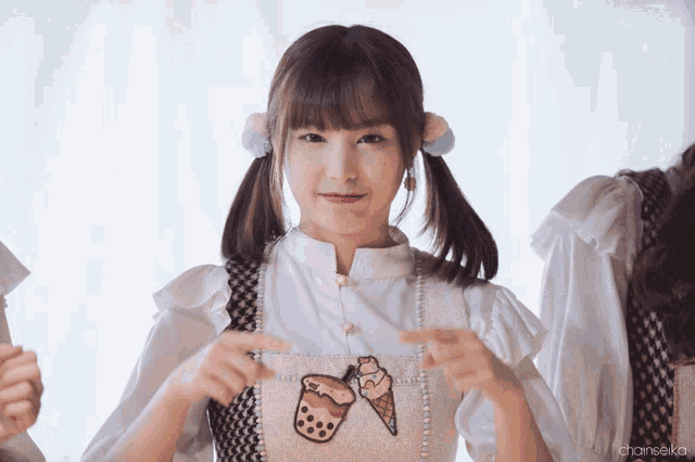 a girl with pigtails is pointing to a picture of an ice cream cone on her shirt