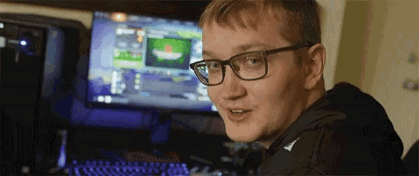 a man wearing glasses sits in front of a computer screen