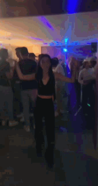 a woman in a black crop top is dancing in a crowd