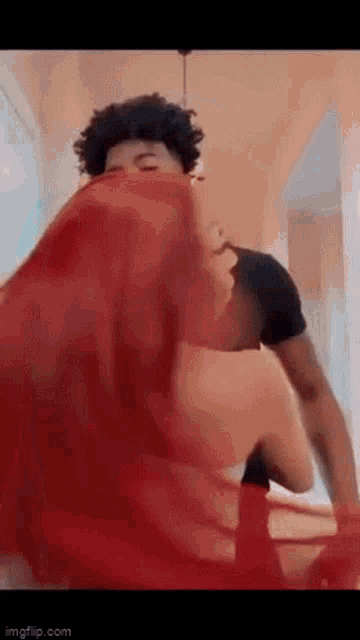 a man is covering his face with a red cloth while a woman is standing next to him .