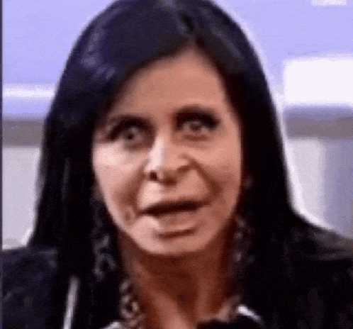 a woman with long black hair is making a funny face while looking at the camera .