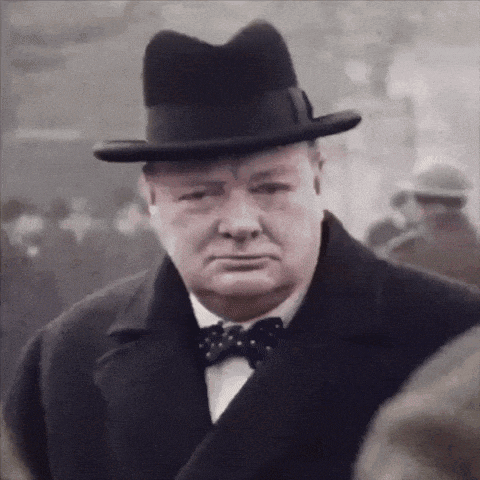 a man wearing a hat and a bow tie looks to the side