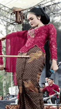 a woman in a red top and brown skirt is dancing