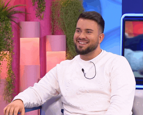 a man with a beard wearing a white sweater that says superdry