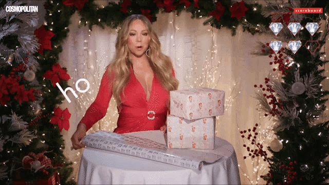 a woman in a red dress is wrapping presents in front of a christmas tree and a sign that says cosmopolitan