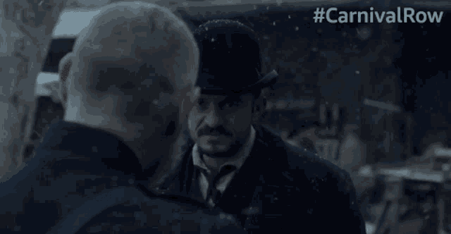 a man with a beard is looking at another man in a car with #carnivalrow written on the bottom
