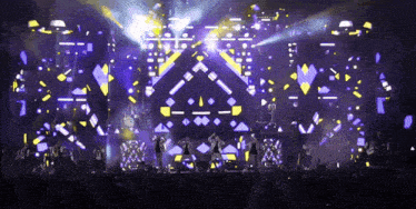 a group of people are standing on a stage with a purple and yellow background