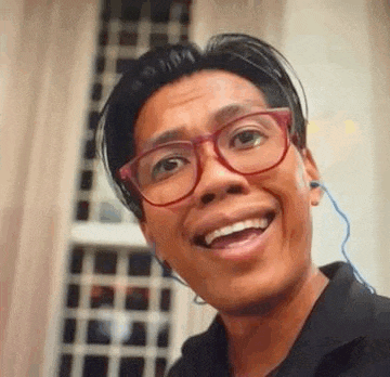 a man wearing glasses and ear buds is smiling and looking at the camera .