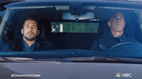 two men are sitting in a car with the nbc logo on the bottom right