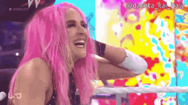 a woman with pink hair is smiling in a ring