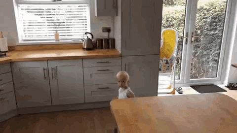 a little girl is sitting in a high chair in a kitchen .
