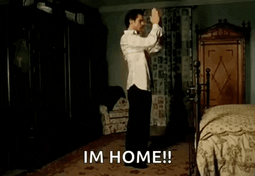 a shirtless man is dancing with a dog in a bedroom and the words `` im home '' are visible .