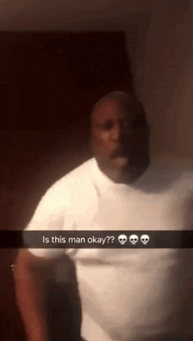 a man in a white shirt is standing in a dark room with a snapchat caption that says is this man okay ?