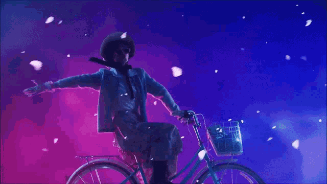 a woman in a white dress is riding a bike with petals falling from the sky