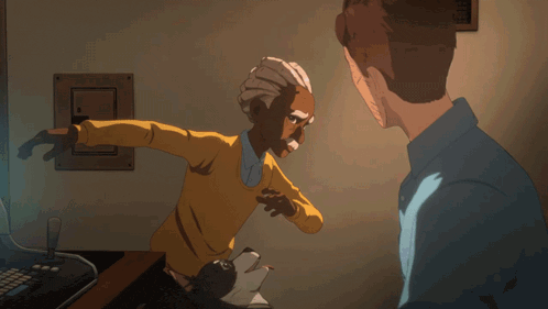 a man sitting on a stool in front of a computer while another man stands on the floor