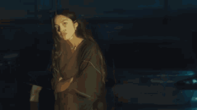 a woman with long hair is standing in a dark room