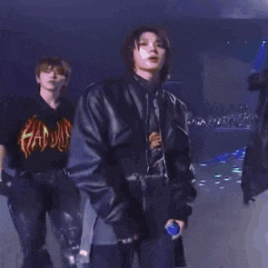 a man in a black leather jacket is standing next to another man in a black shirt on a stage .
