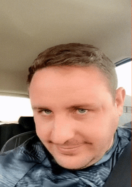 a man sitting in a car with a gray shirt on