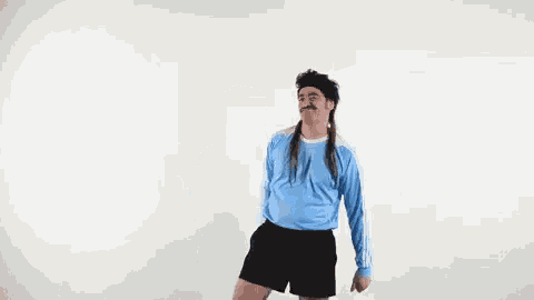 a man wearing a blue shirt and black shorts is dancing .