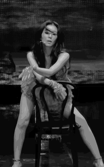 a woman in a dress is sitting on a chair on a stage .