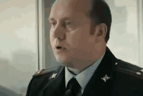 a man in a military uniform and tie is looking at the camera with his mouth open .