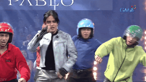 a group of men wearing helmets are dancing in front of a sign that says pablo