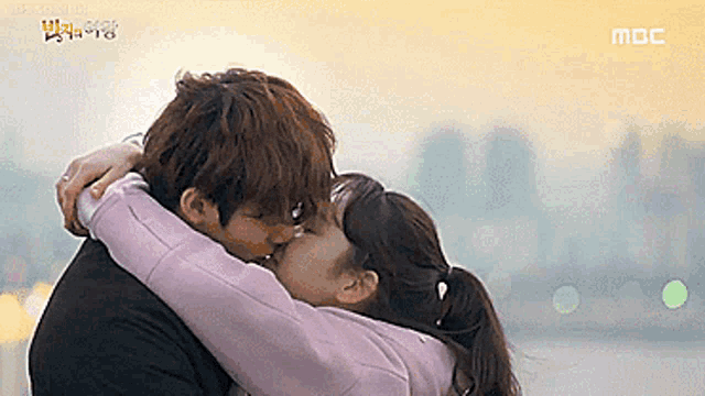 a man and a woman are kissing while hugging each other .