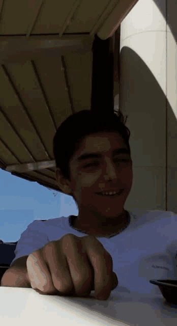 a young man sitting at a table with his hand on his face
