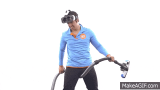 a man wearing a virtual reality headset holds a vacuum cleaner