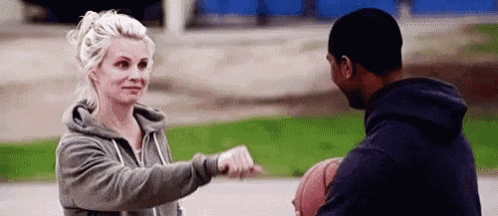 a man and a woman are playing basketball on a court and the woman is holding the basketball .
