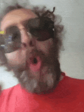 a man with a beard wearing a red shirt and sunglasses