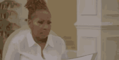 a woman in a white shirt is sitting at a table holding a piece of paper in her hand .