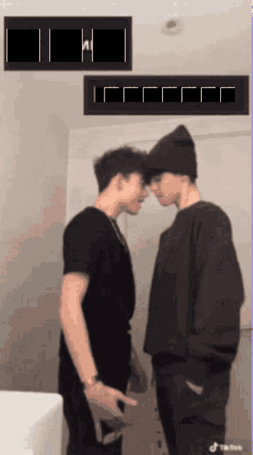 two young men are standing next to each other and looking at each other in front of a sign that says " tiktok "