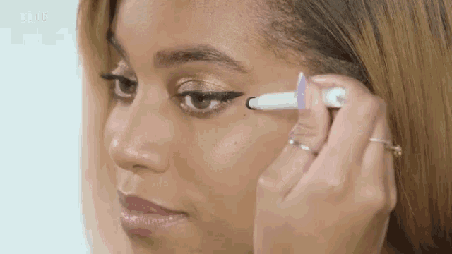 a close up of a woman applying eyeliner with a marker .
