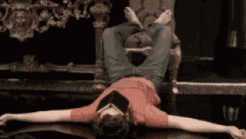 a man in a red shirt is laying on his back with his legs crossed and a book on his head .