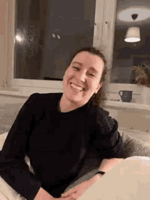 a woman is sitting on a couch and smiling .