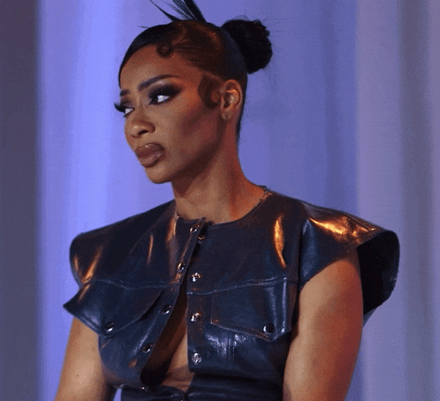 a woman with a bun on her head wears a black leather jacket