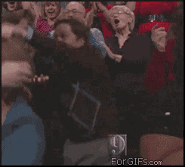 a woman in a black shirt with the number 9 on it is screaming in a crowd of people